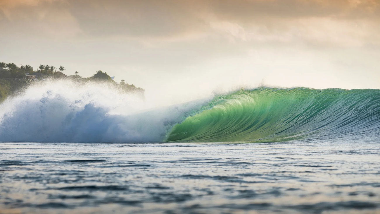 Large wave in the ocean with a rainbow in the background