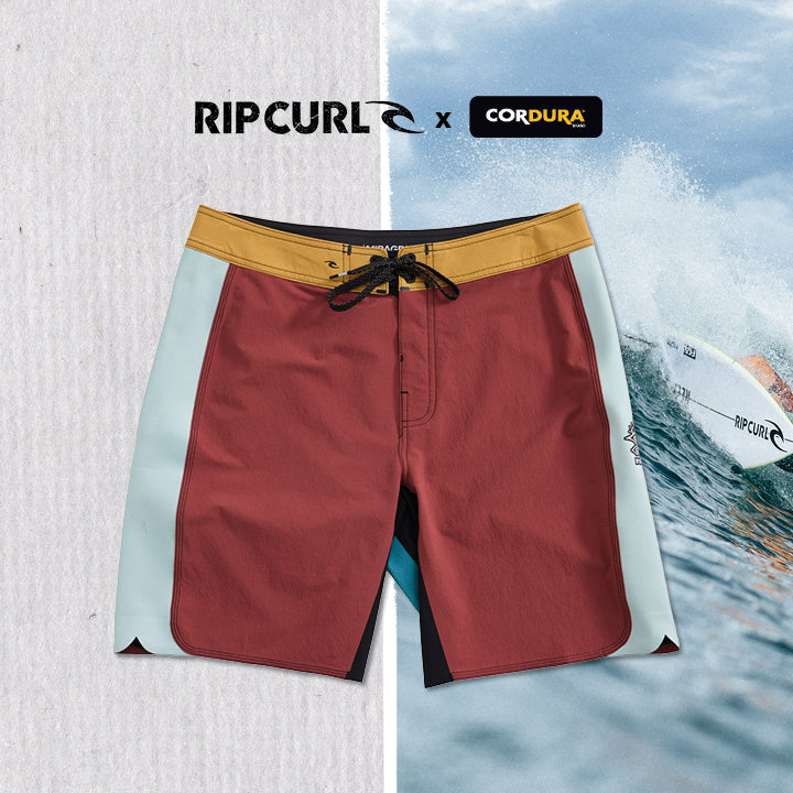 Red board shorts with yellow waistband on a white background, featuring Rip Curl and Cordura logos.