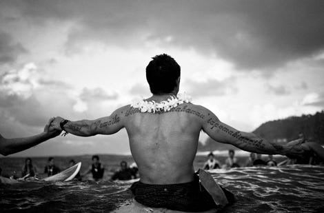 Black and white image of surfer sitting on his board