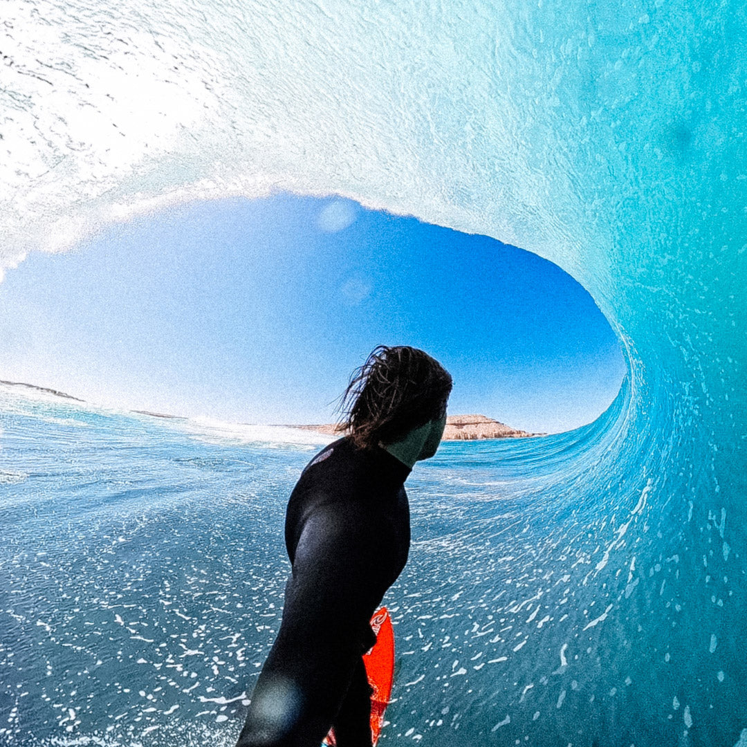 Person in a wetsuit inside a wave tunnel with clear blue water