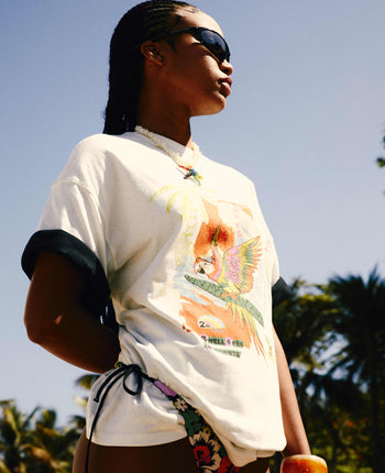 Person wearing a white t-shirt with colorful graphics outdoors