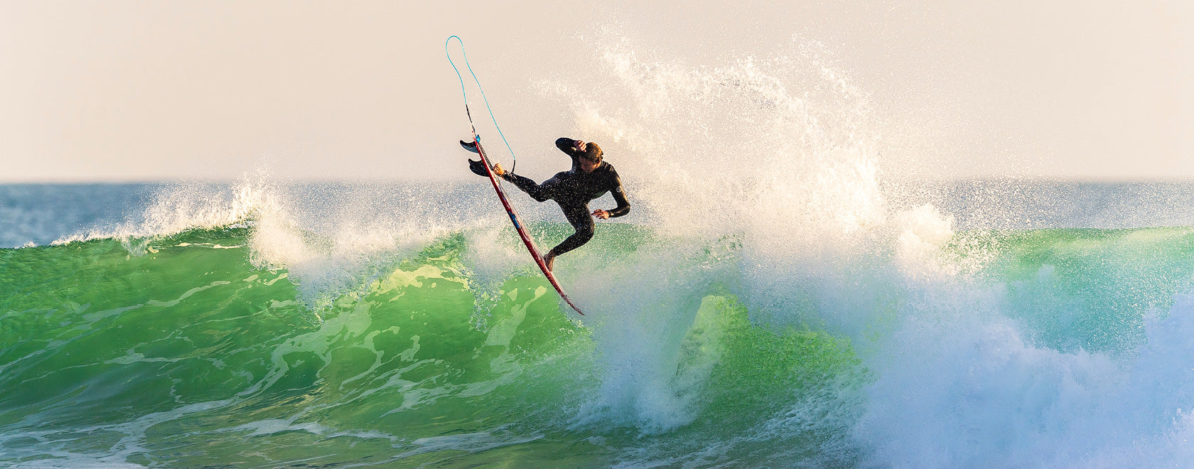 Surfer riding a wave on a surfboard with a clear sky background