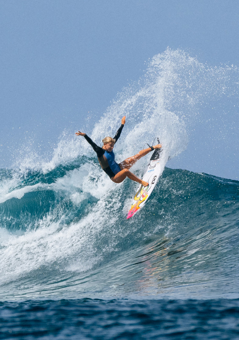 Person surfing on a wave with a clear blue sky