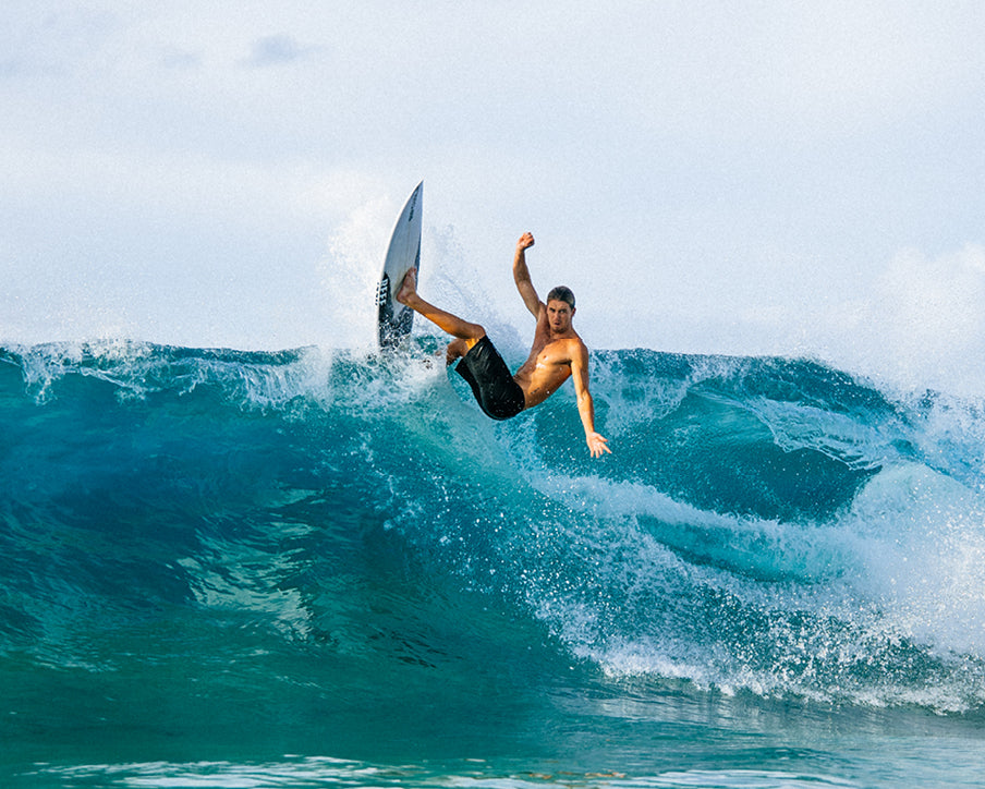Surfer performing a trick on a wave with a clear sky background