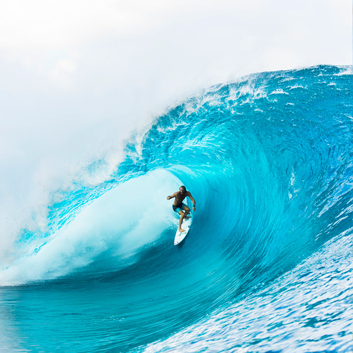 Surfer riding a large blue wave in the ocean