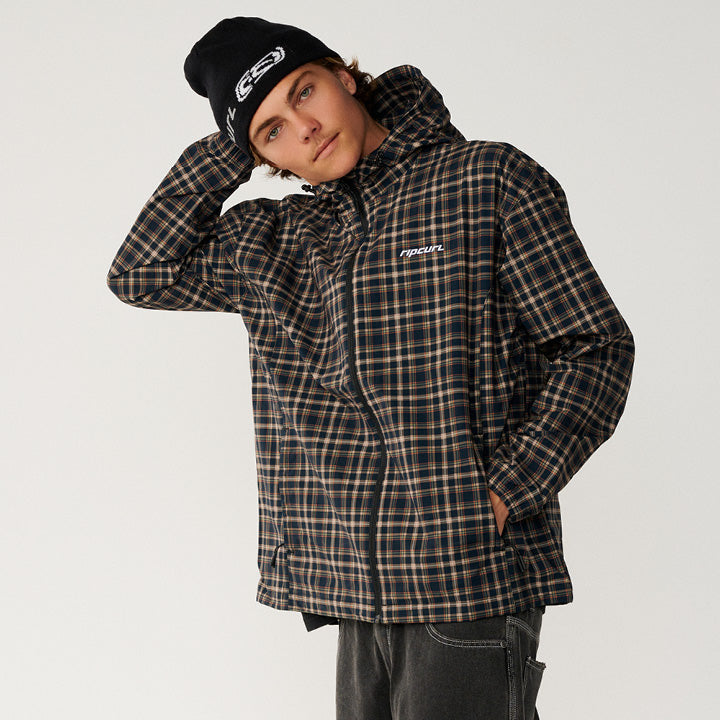 A model wearing a black and brown plaid hooded jacket with a white chest logo, paired with a black beanie, against a plain light gray background.