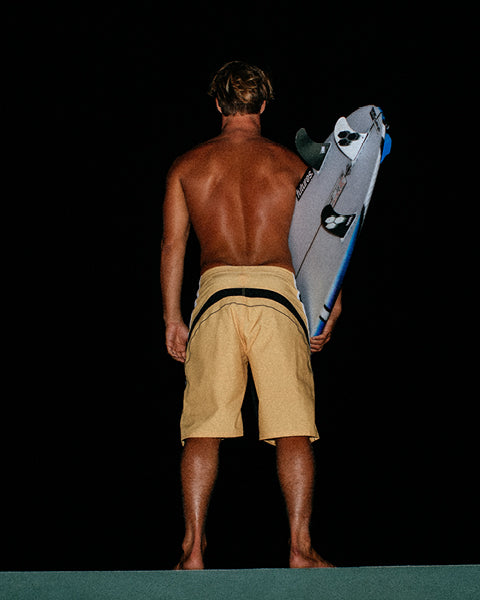 Man holding a surfboard with a black background