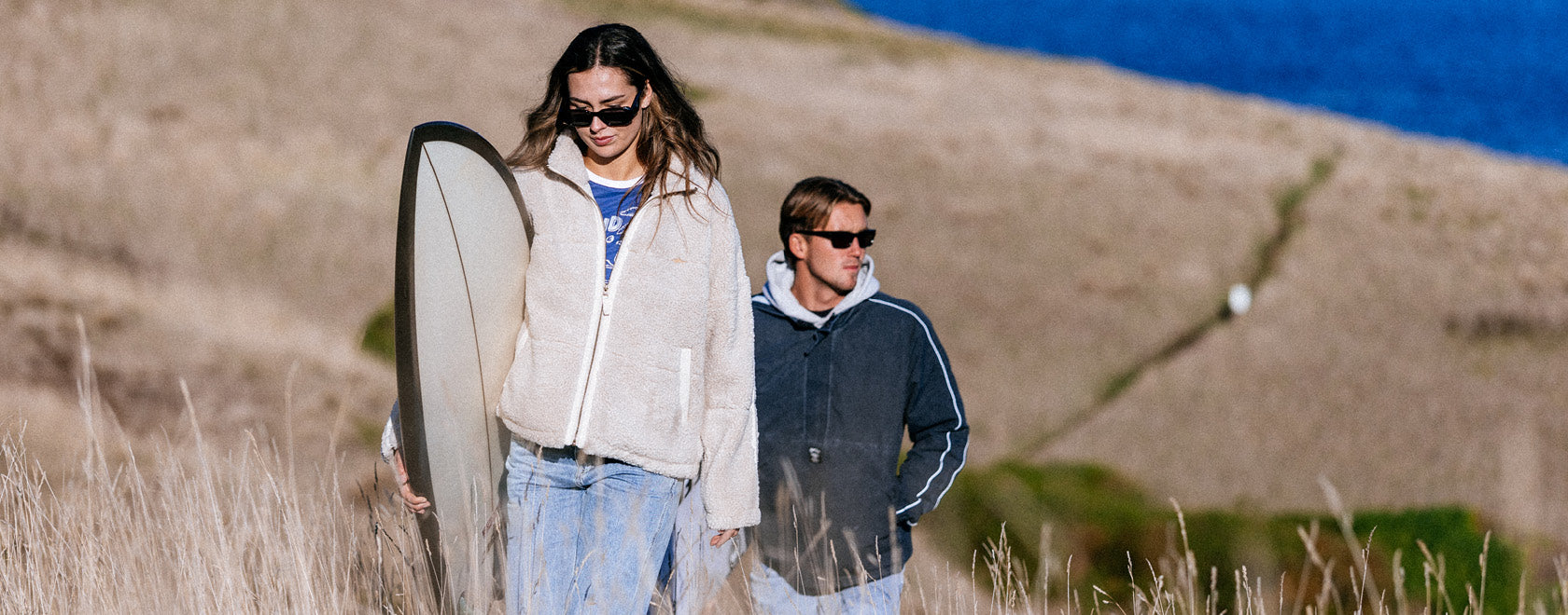 Two people walking with a surfboard on a beach