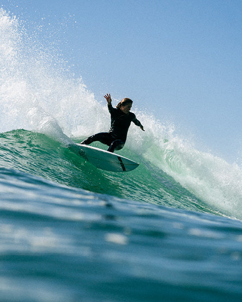 Person surfing on a wave with clear blue sky