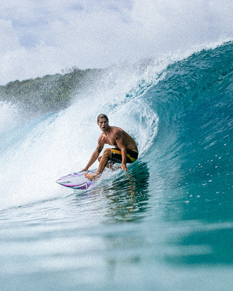 Person surfing on a wave in clear blue water