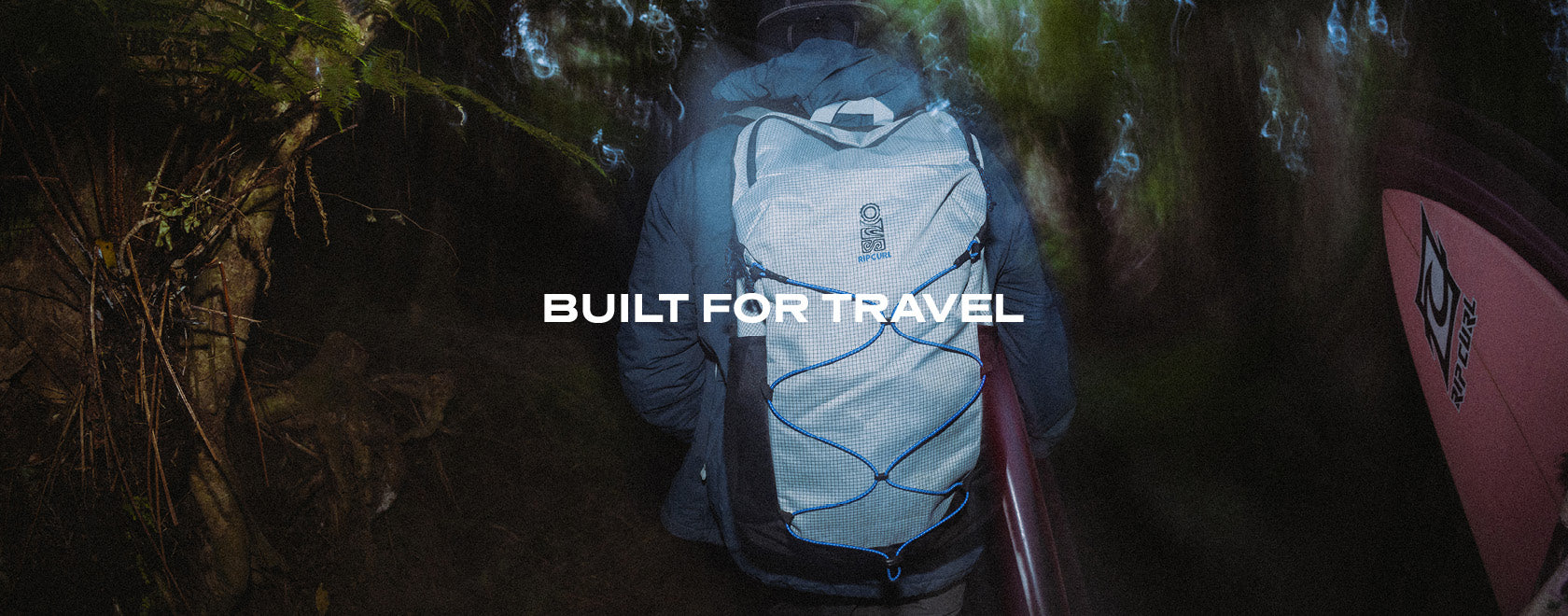 A person wearing a light blue and white backpack walks through a dark forest at night, with the text 'BUILT FOR TRAVEL' overlaid across the center.