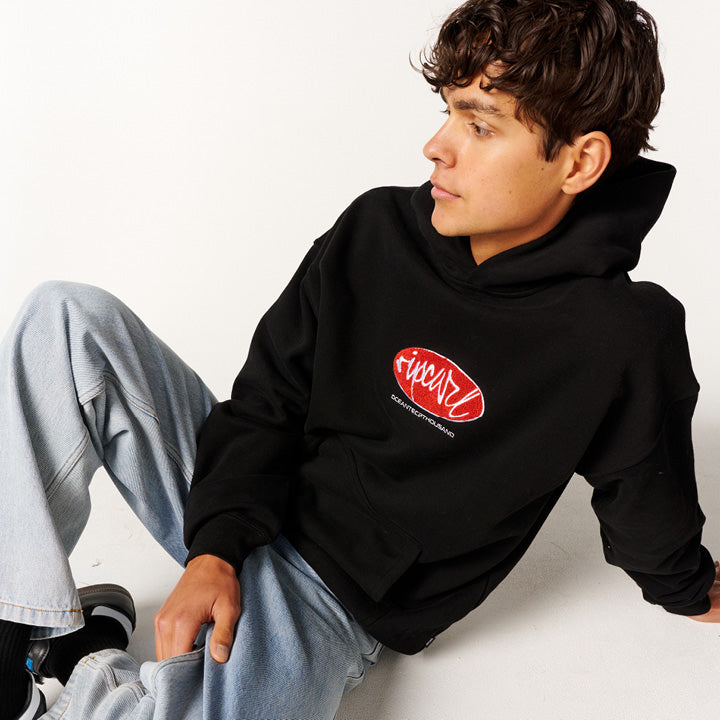 Model wearing a black hoodie with a red logo