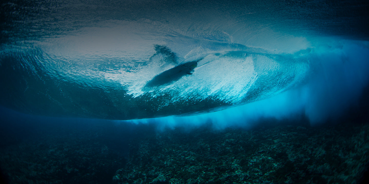 Underwater view of a large wave with a surfer surfing