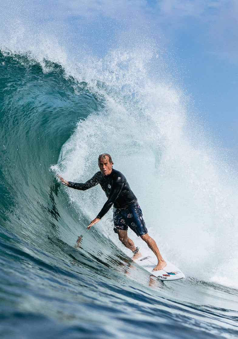 Surfer riding a wave in the ocean with clear blue sky.